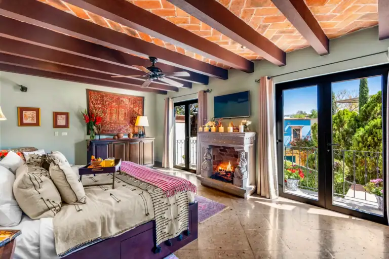 Casa Cleo Petra, bedroom with a fireplace and doors to a balcony, San Miguel de Allende