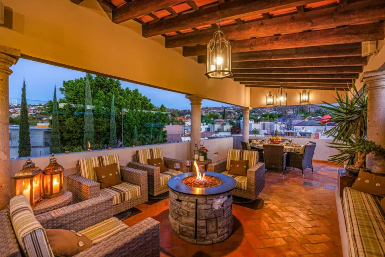 Casa Cleo Petra, covered rooftop terrace with a fire pit and wicker sofas at dusk, San Miguel de Allende