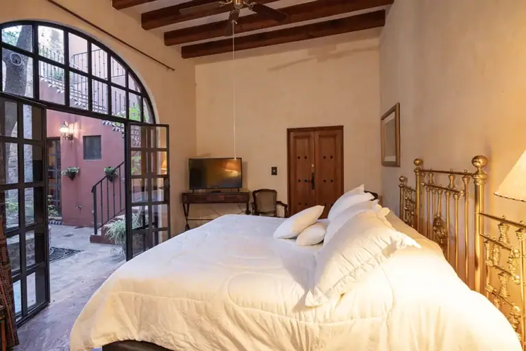 Casa Colonial, bedroom with a brass bed and arched steel-framed windows, San Miguel de Allende