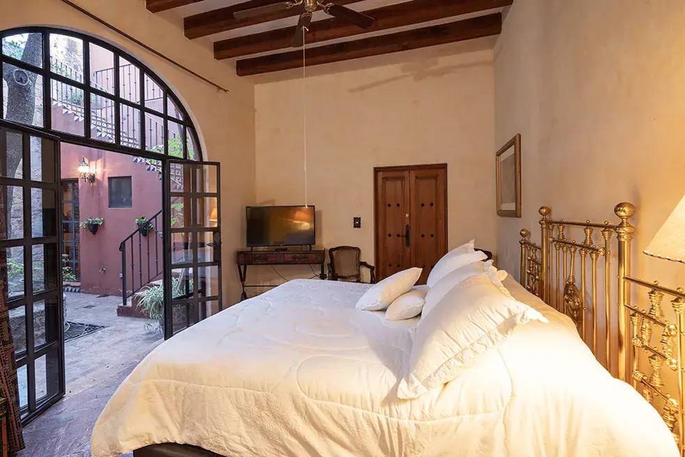 Casa Colonial, bedroom with a brass bed and arched steel-framed windows, San Miguel de Allende