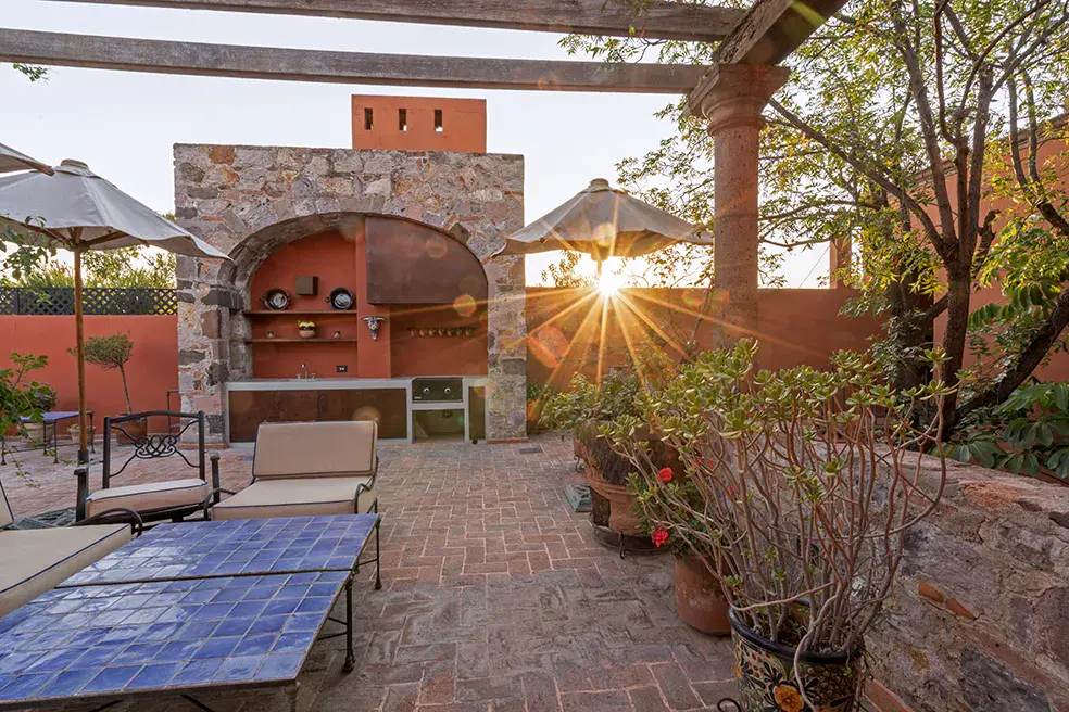 Casa Colonial, terrace at sunset with a stone barbecue arch and a blue tile table, San Miguel de Allende