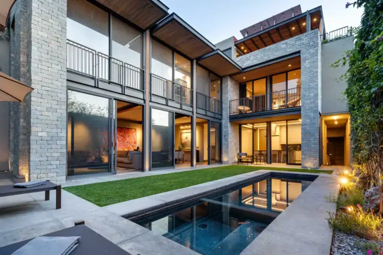 Casa Core, glass-walled two-story house glowing at dusk behind a lawn and a narrow plunge pool, San Miguel de Allende