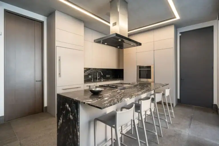Casa Core, kitchen with a black granite island, white bar stools and a stainless range hood, San Miguel de Allende