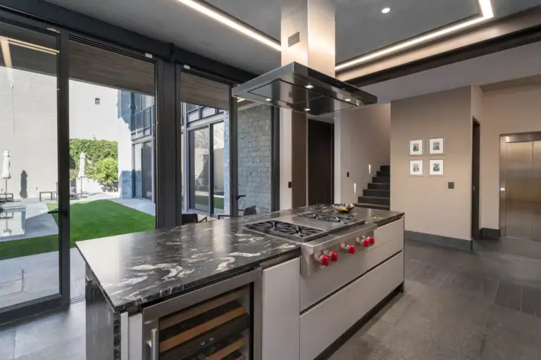 Casa Core, kitchen island with a gas cooktop and a view to the garden through sliding glass, San Miguel de Allende