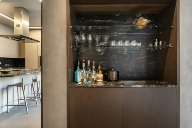 Casa Core, built-in bar with black stone backsplash and glass shelves of glasses and bottles, San Miguel de Allende