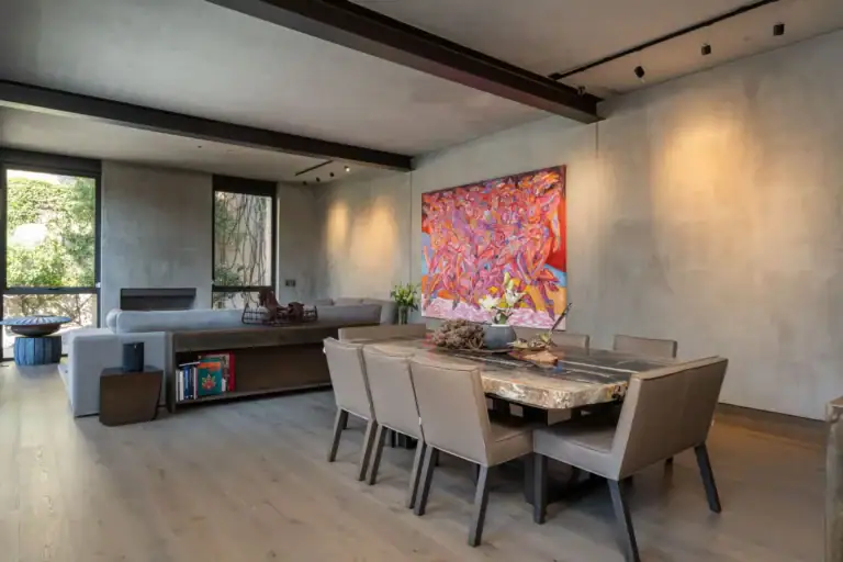 Casa Core, dining and living area with a live-edge table, concrete walls and a large pink abstract painting, San Miguel de Allende