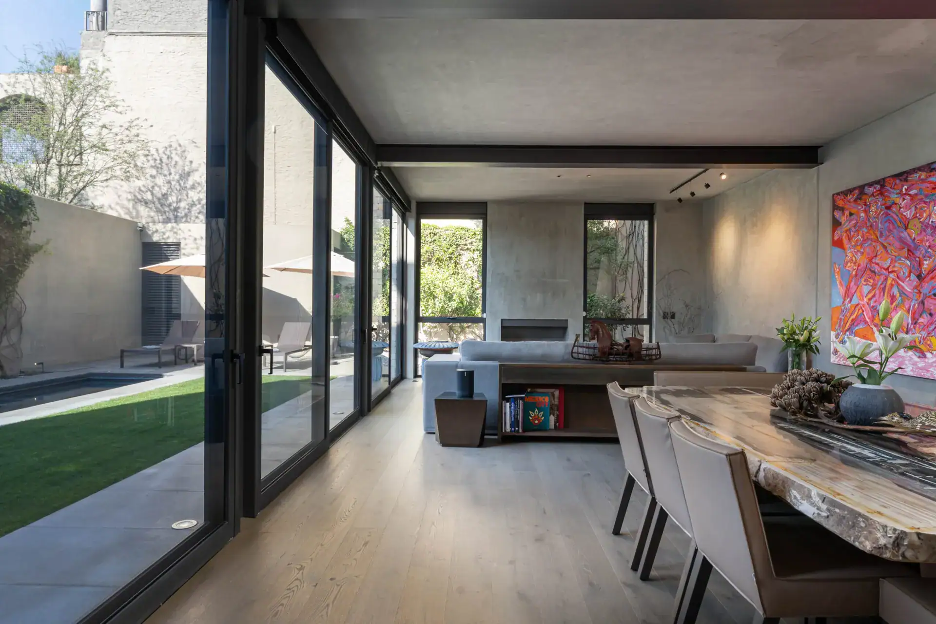 Casa Core, open living room with sliding glass walls to the courtyard and a long dining table, San Miguel de Allende