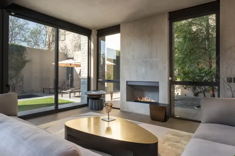 Casa Core, living room with a gas fireplace between tall windows facing the lawn, San Miguel de Allende