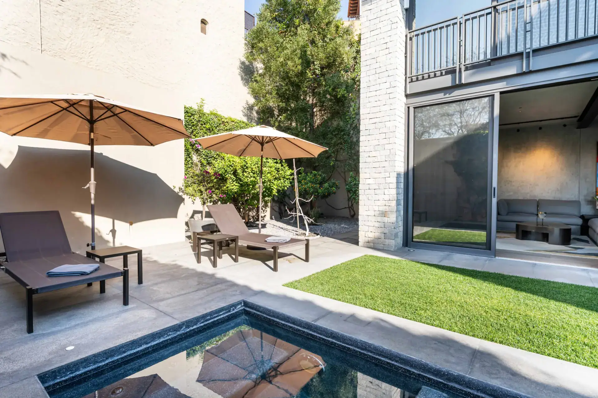 Casa Core, patio lounge chairs and umbrellas beside the pool and lawn, San Miguel de Allende