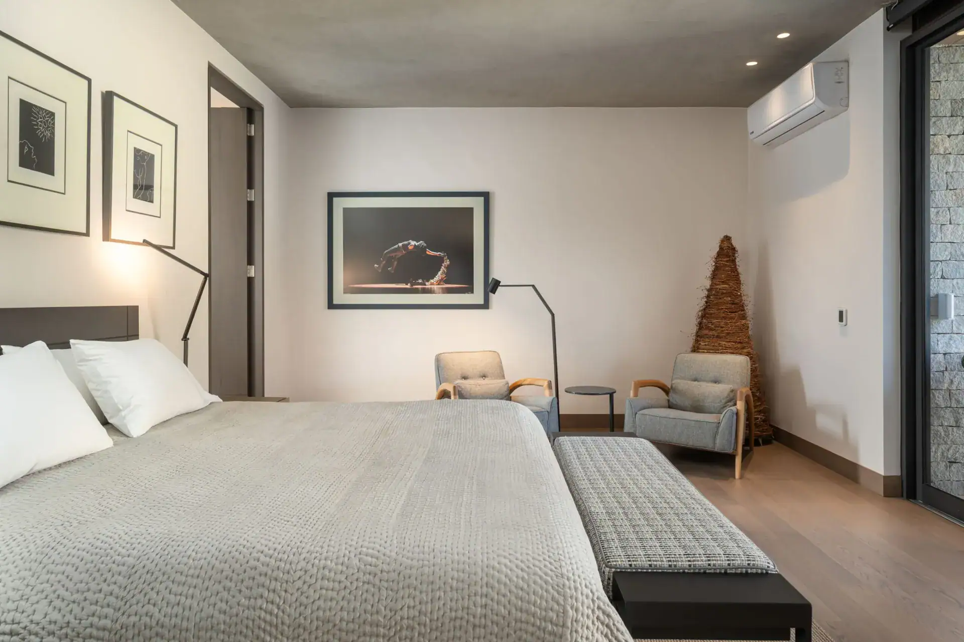 Casa Core, bedroom with a quilted bedspread, bench, armchairs and framed artwork, San Miguel de Allende