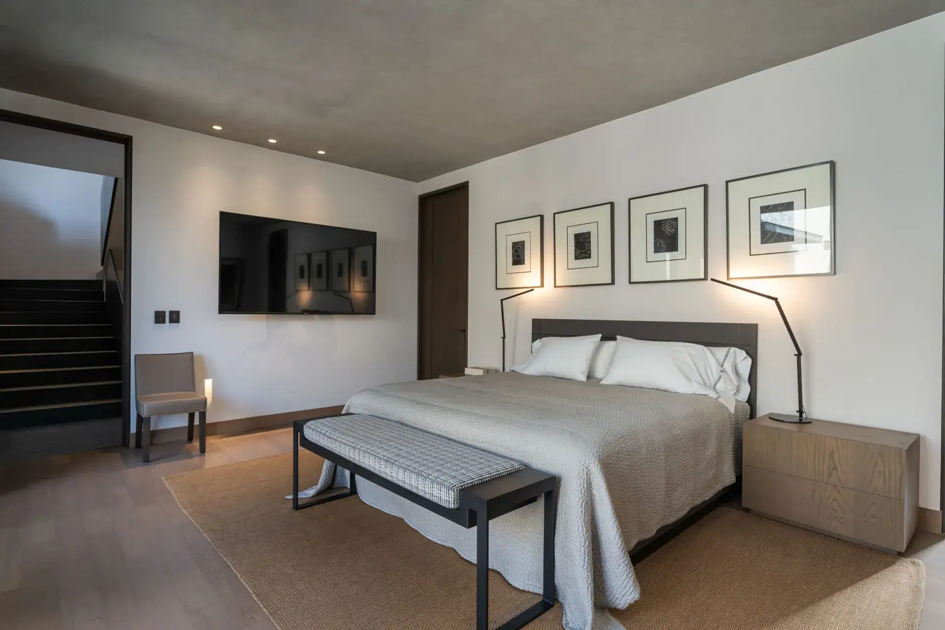 Casa Core, main bedroom with framed prints, a television and a staircase landing, San Miguel de Allende