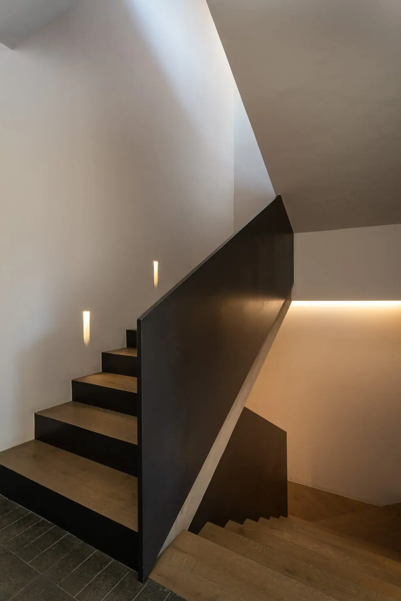 Casa Core, wood and black-steel staircase with a lit wall niche, San Miguel de Allende