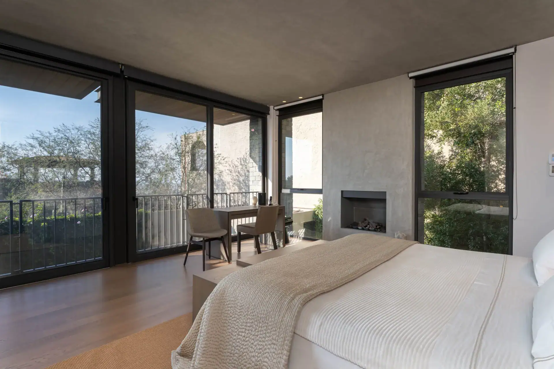 Casa Core, bedroom with sliding glass doors, a desk and a fireplace framed by trees, San Miguel de Allende