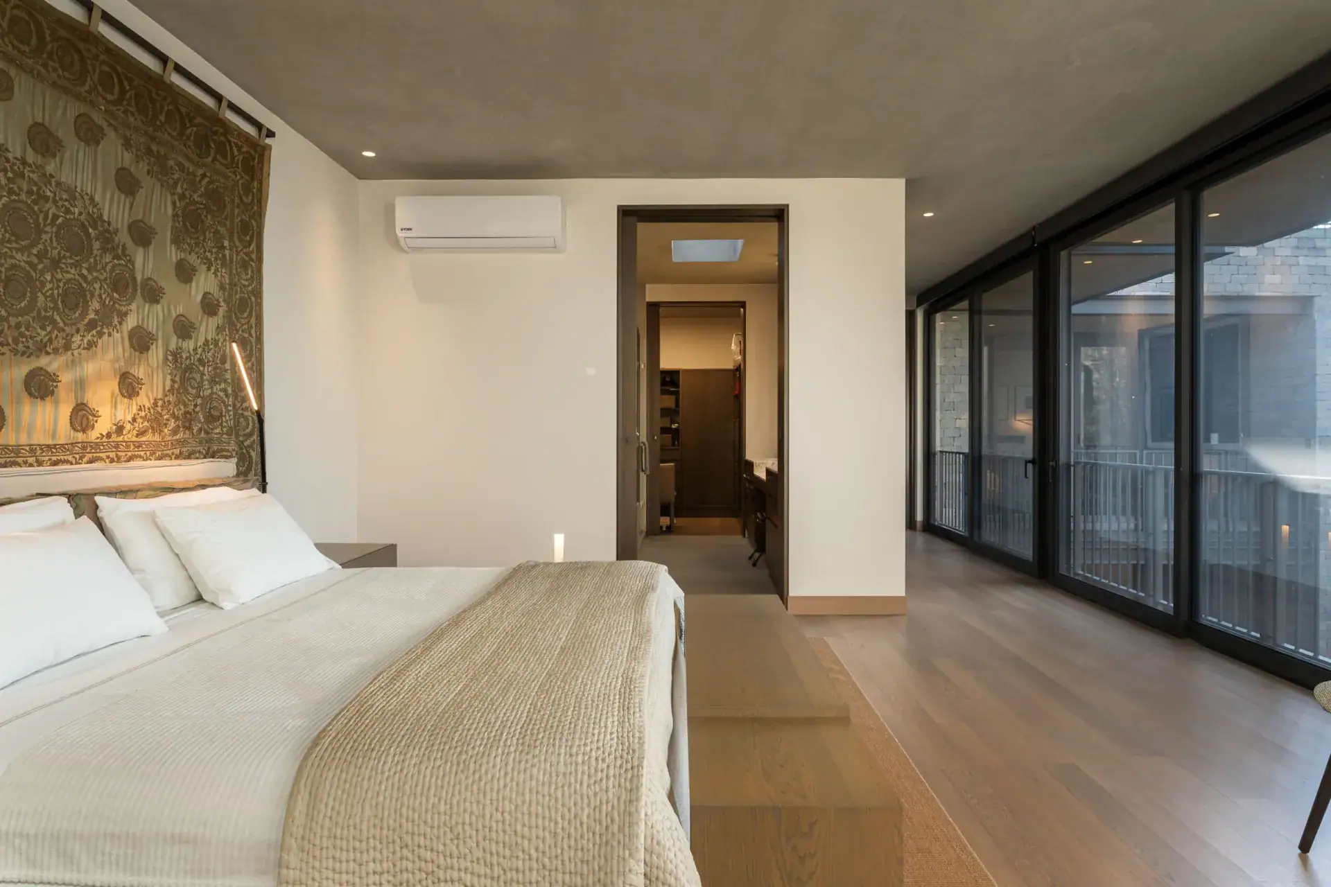 Casa Core, bedroom with a tapestry headboard wall and an open doorway to the dressing area, San Miguel de Allende