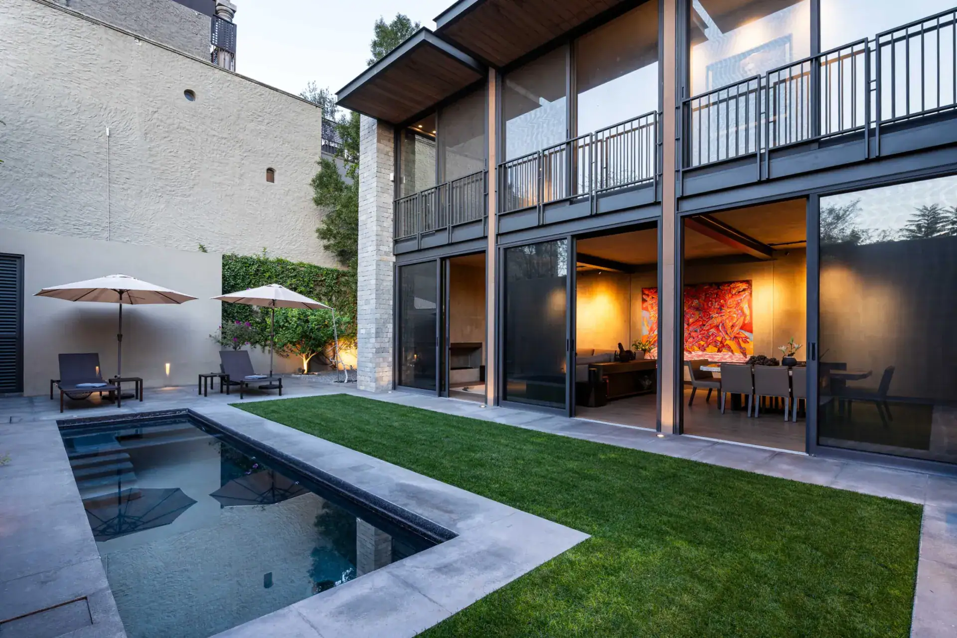 Casa Core, courtyard with a plunge pool, lawn and umbrellas in front of the glass-walled dining room, San Miguel de Allende