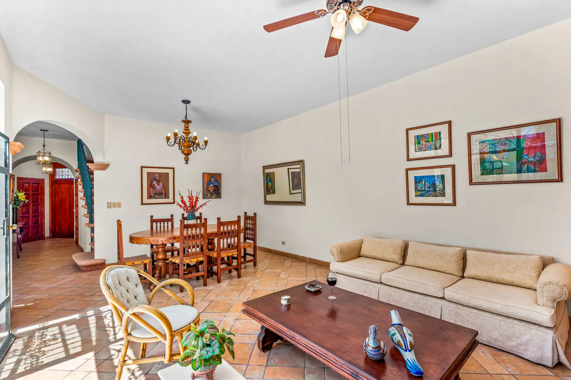 Casa Cul-De-Sac Armonia, living and dining room with a long sofa, a dark wood dining table with chairs and an arched hallway, San Miguel de Allende