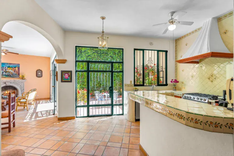 Casa Cul-De-Sac Armonia, kitchen with a hand-painted tile counter, a white range hood, a gas range and a view to the fireplace room, San Miguel de Allende