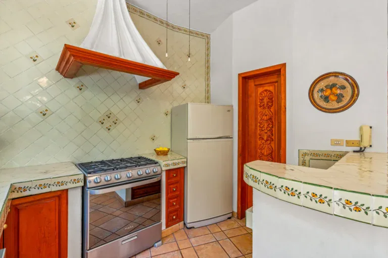 Casa Cul-De-Sac Armonia, kitchen with a white pyramid range hood, diagonal painted tile, a gas range and a refrigerator, San Miguel de Allende