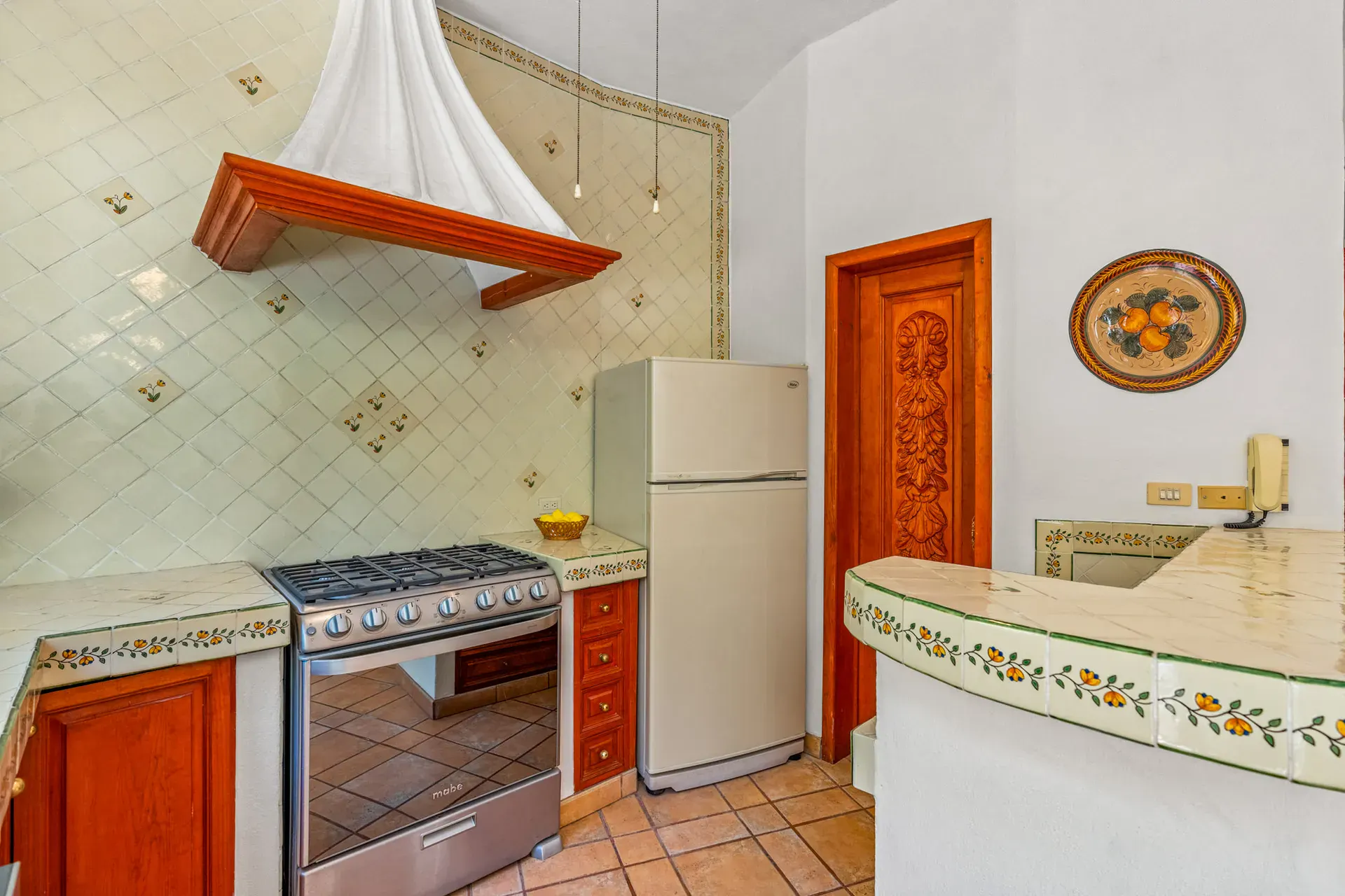 Casa Cul-De-Sac Armonia, kitchen with a white pyramid range hood, diagonal painted tile, a gas range and a refrigerator, San Miguel de Allende