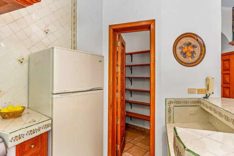 Casa Cul-De-Sac Armonia, kitchen corner with a white refrigerator, a pantry with shelves and a hand-painted tile counter, San Miguel de Allende