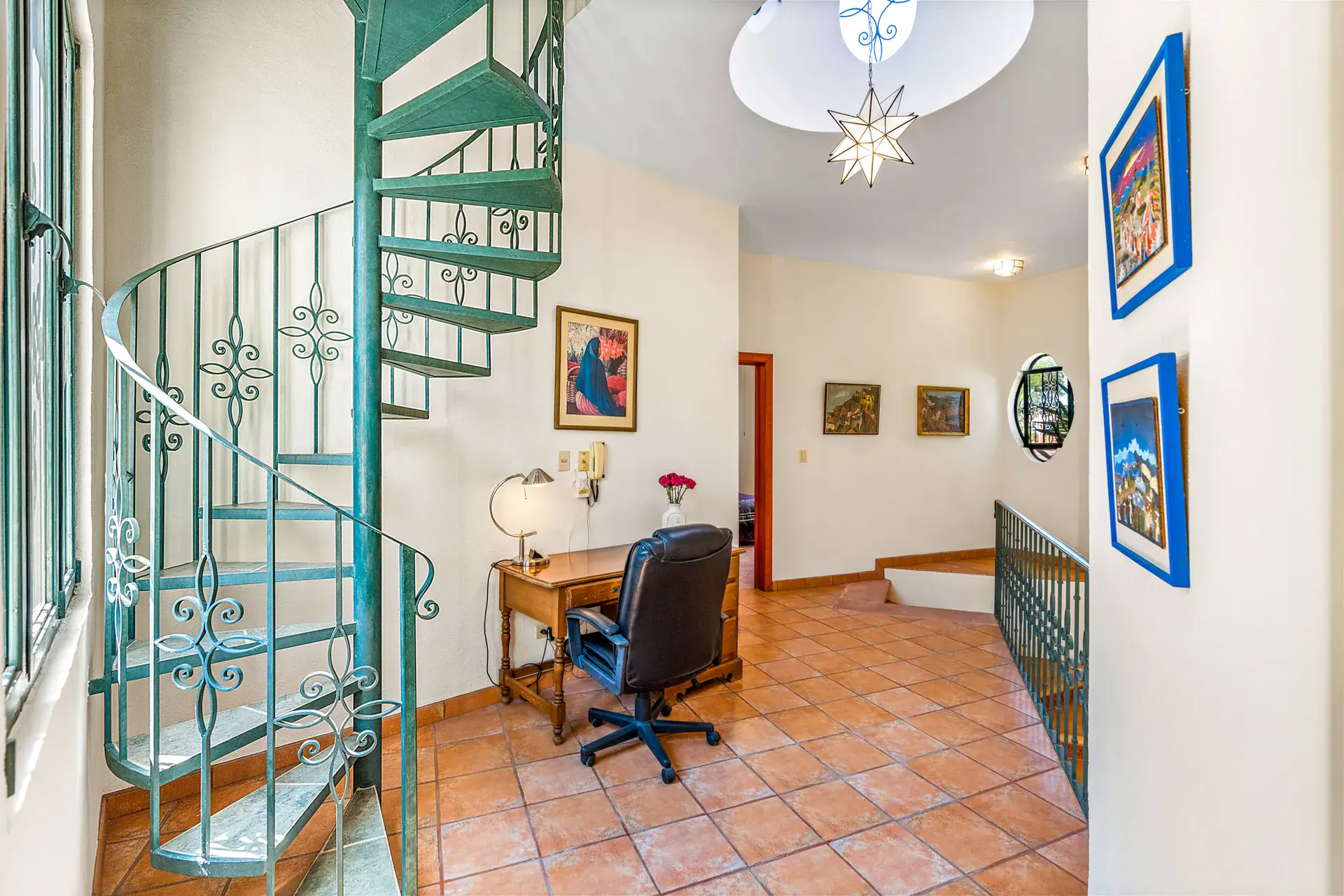 Casa Cul-De-Sac Armonia, upstairs sitting area with a green spiral staircase, a desk, a star lantern and paintings, San Miguel de Allende