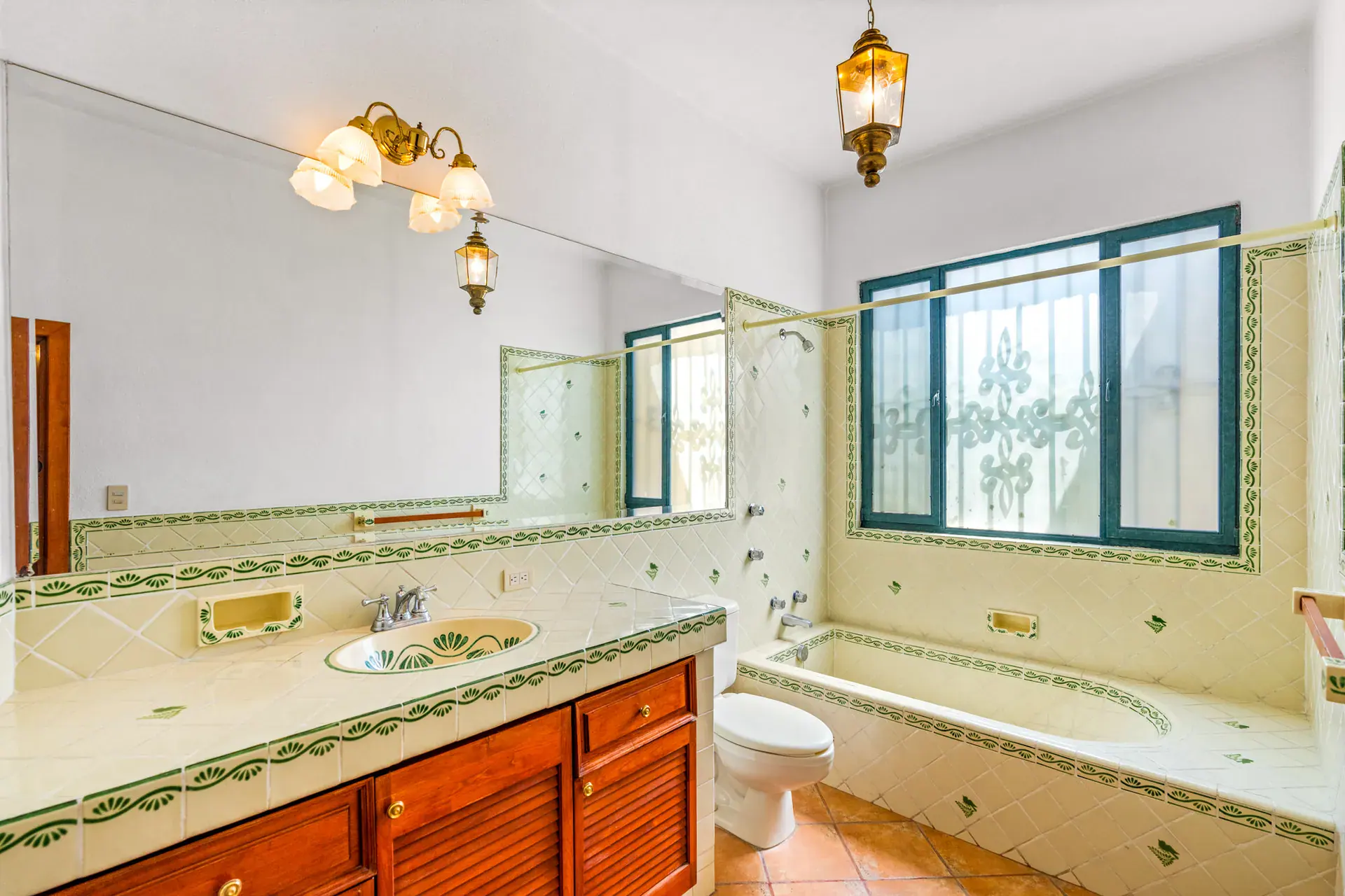 Casa Cul-De-Sac Armonia, bathroom with a mirrored wall, a blue-edged tile tub and vanity with an arched window, San Miguel de Allende
