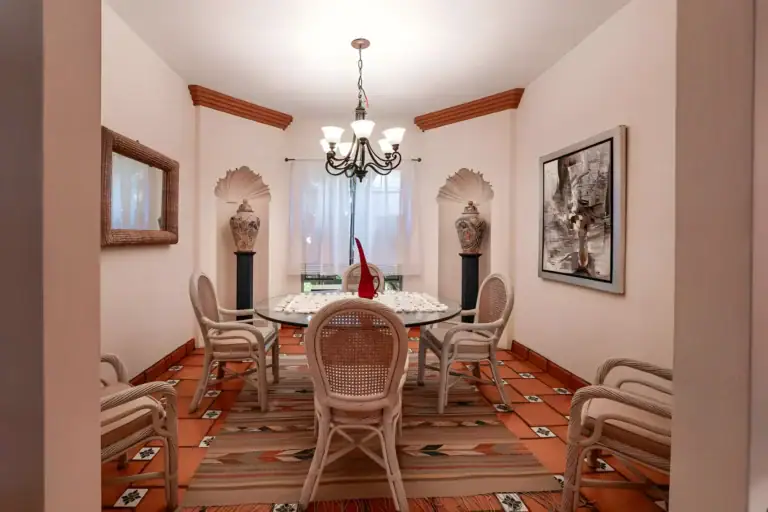 Casa de la Gracia, dining room with a glass-top round table, wicker chairs, shell niches and a chandelier, San Miguel de Allende