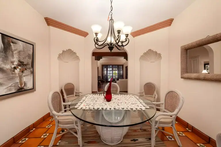 Casa de la Gracia, dining table with a lace runner and a view through an arch to the living room, San Miguel de Allende