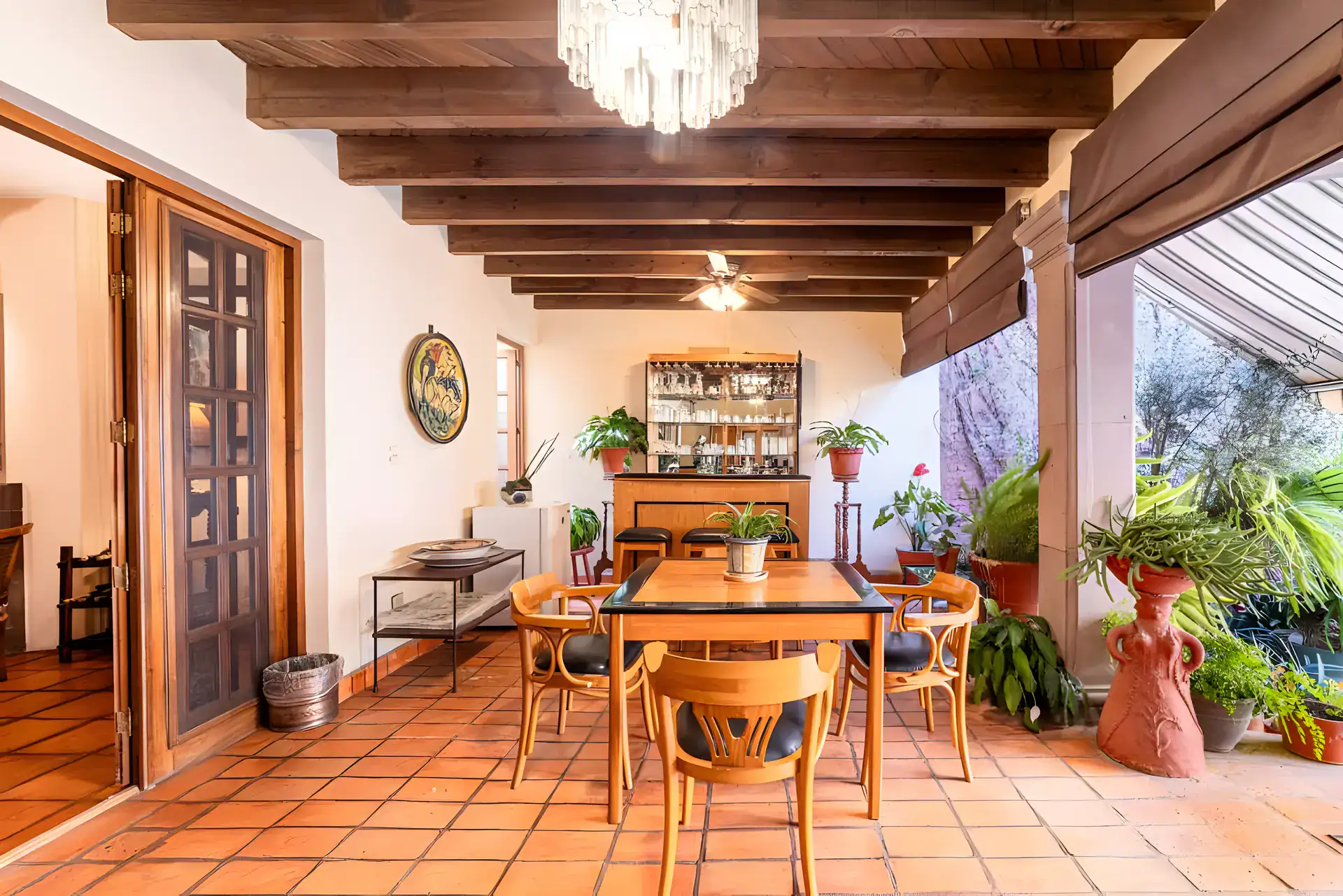 Casa de la Gracia, covered patio dining area with a wood table, a bar cabinet and potted plants under a beamed ceiling, San Miguel de Allende