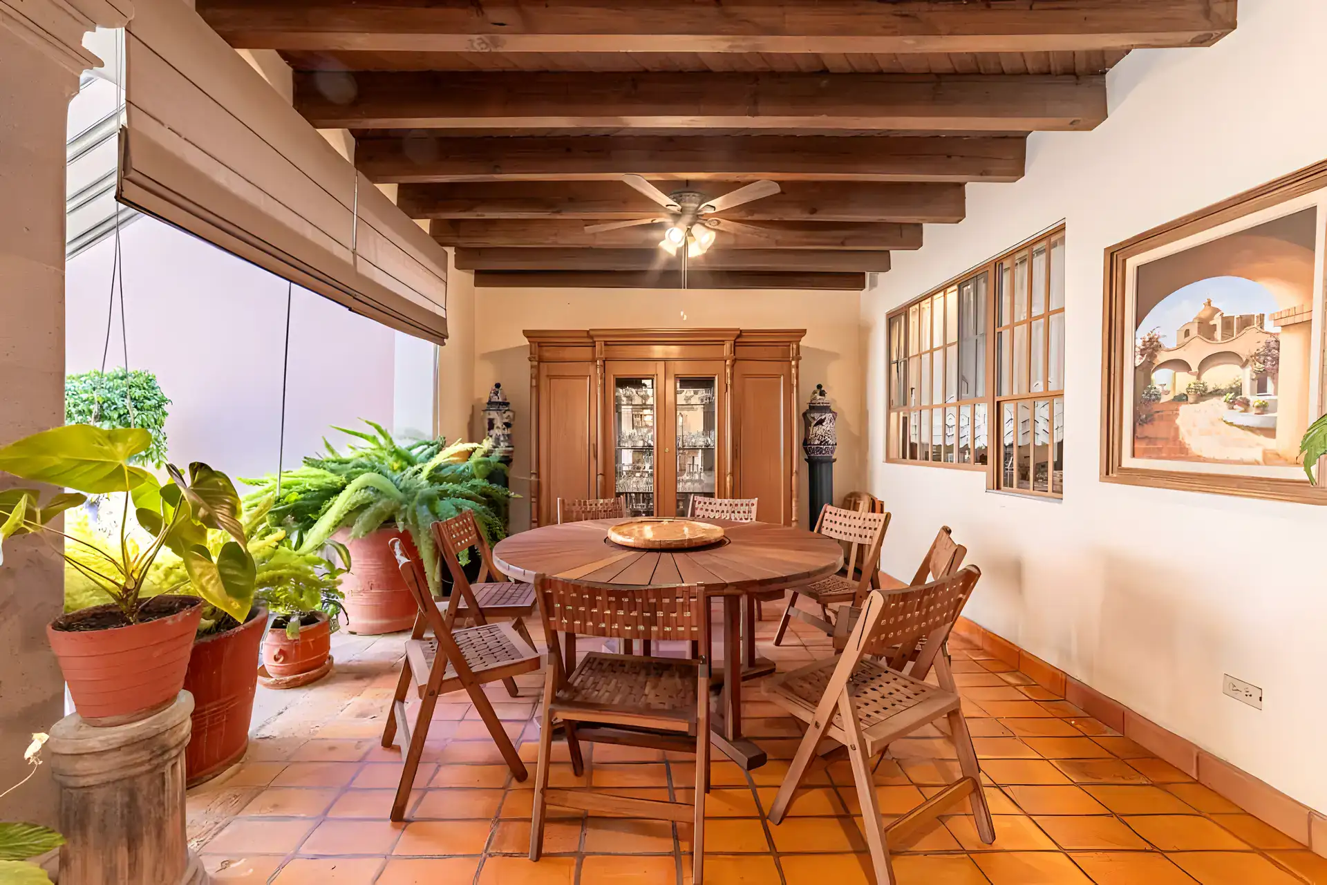 Casa de la Gracia, covered patio with a round wood dining table, a china cabinet and a framed painting, San Miguel de Allende