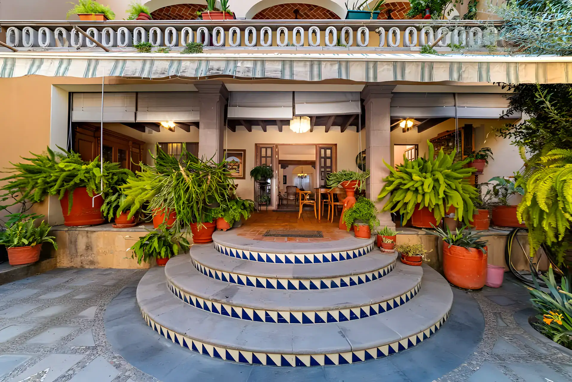 Casa de la Gracia, round tiled steps leading up to a covered terrace with potted ferns, San Miguel de Allende