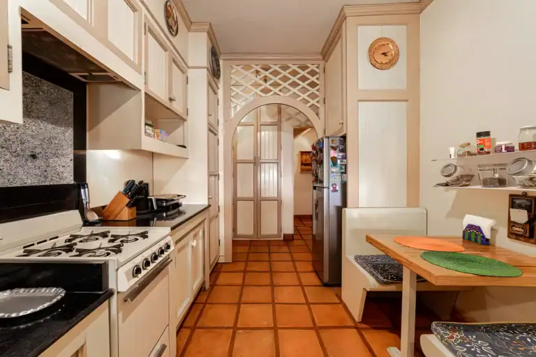 Casa de la Gracia, galley kitchen with a gas range, black granite counters and a breakfast table with bench seating, San Miguel de Allende