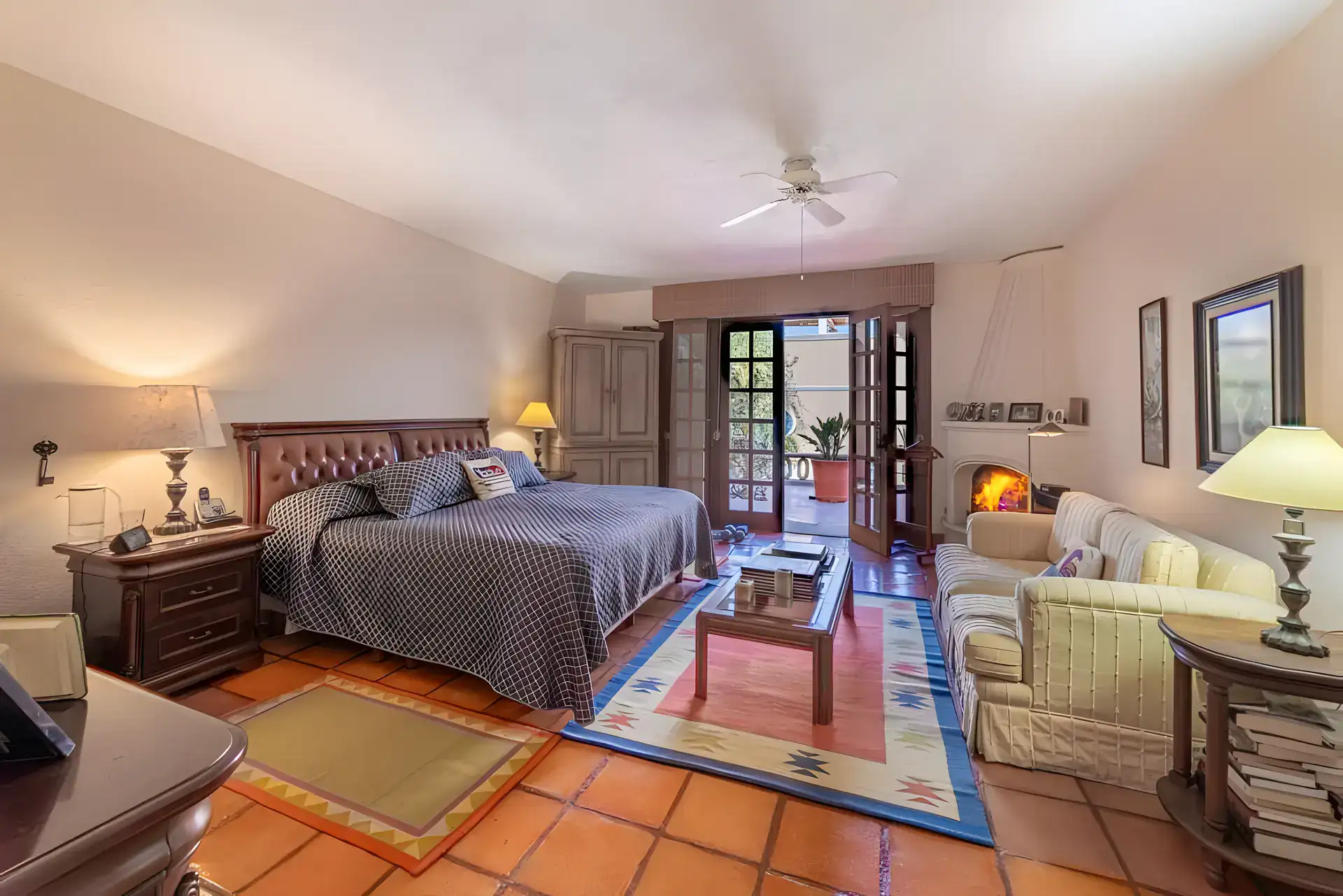 Casa de la Gracia, bedroom with a leather headboard, a seating area, a corner fireplace and French doors to the terrace, San Miguel de Allende