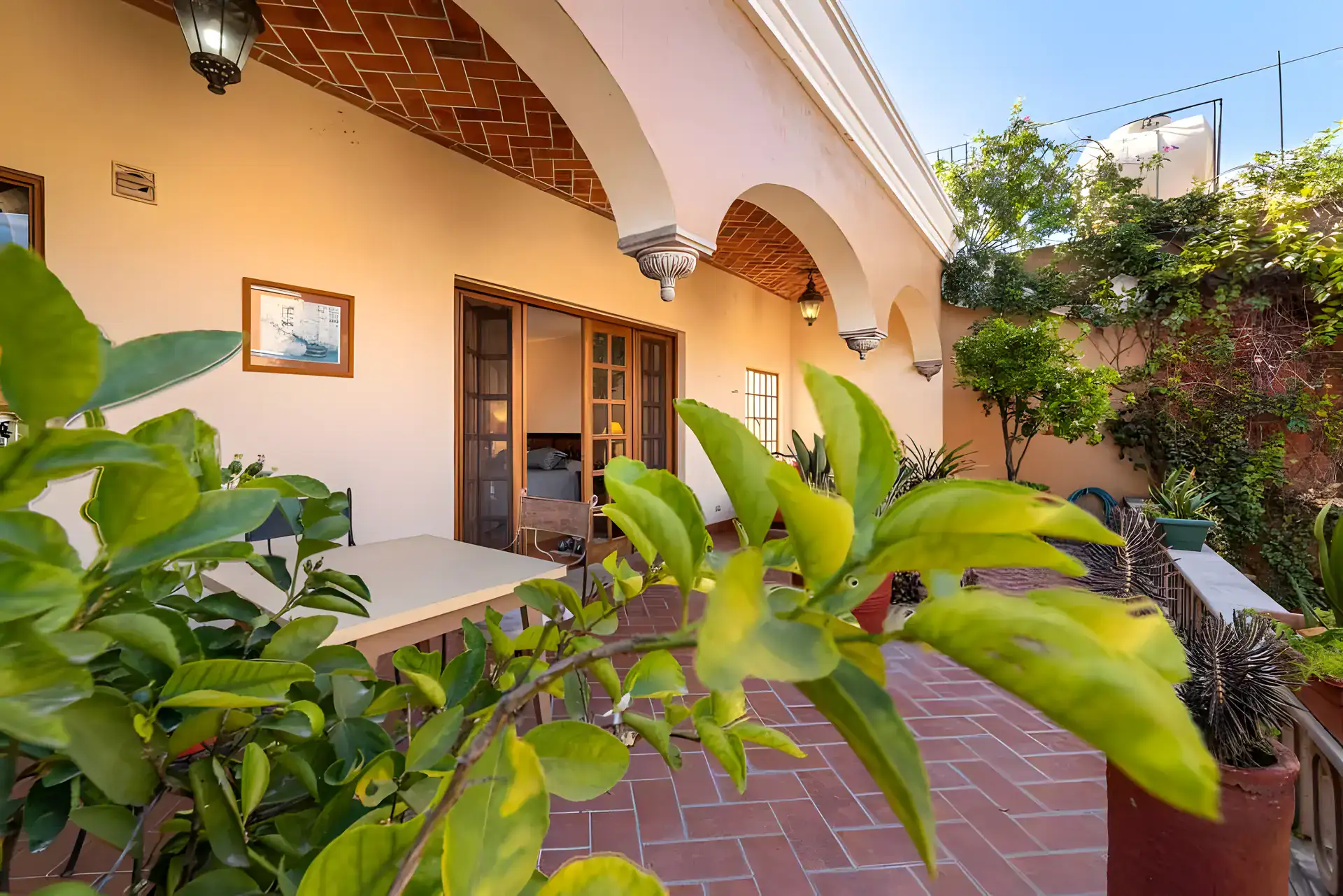 Casa de la Gracia, terrace with a brick floor, a table, a lemon tree and arched doorways, San Miguel de Allende