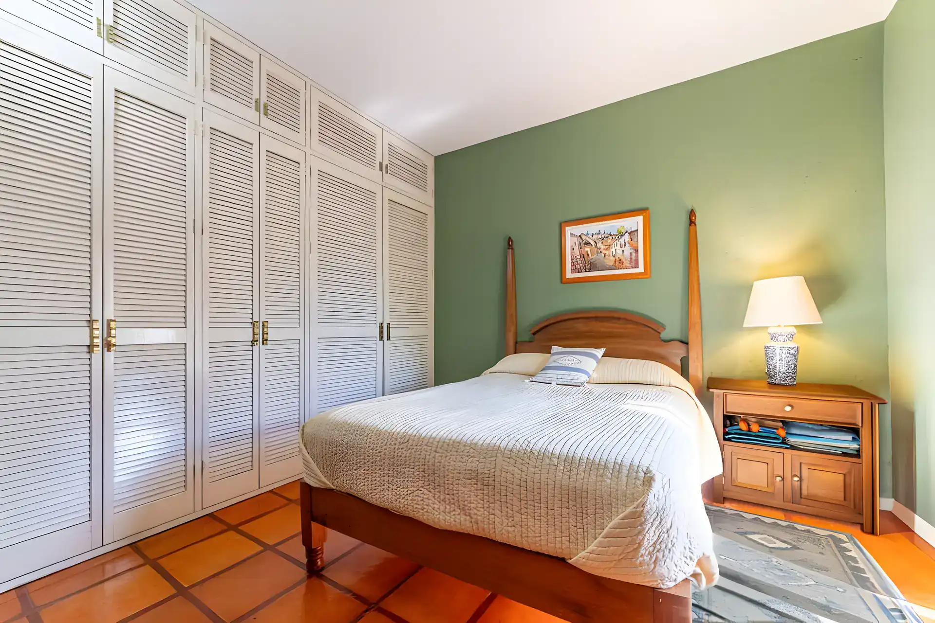 Casa de la Gracia, bedroom with a single bed, a green accent wall, louvered wardrobes and wood bedside table, San Miguel de Allende