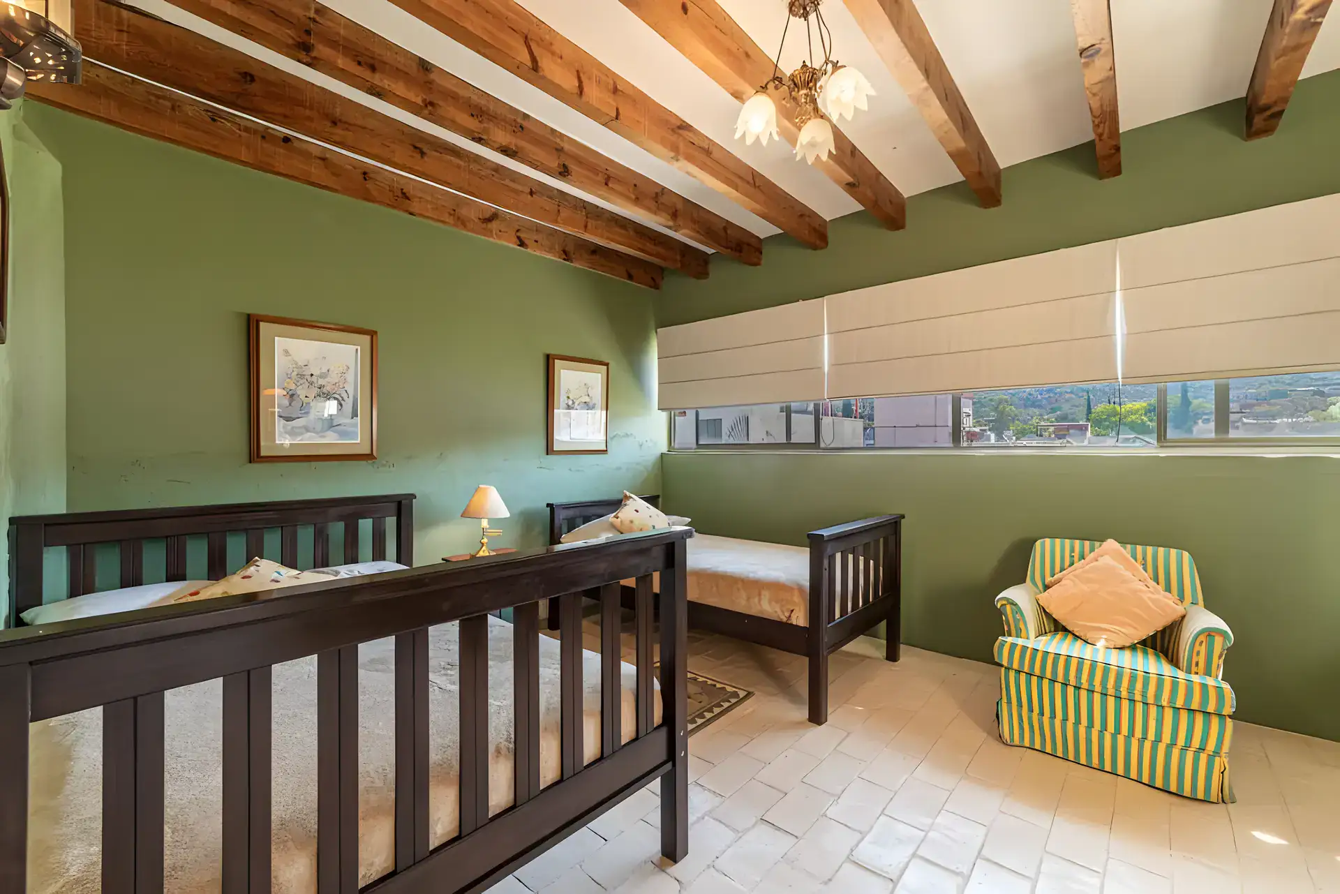 Casa de la Gracia, bedroom with bunk-style beds, a striped armchair and a green wall under a beamed ceiling, San Miguel de Allende
