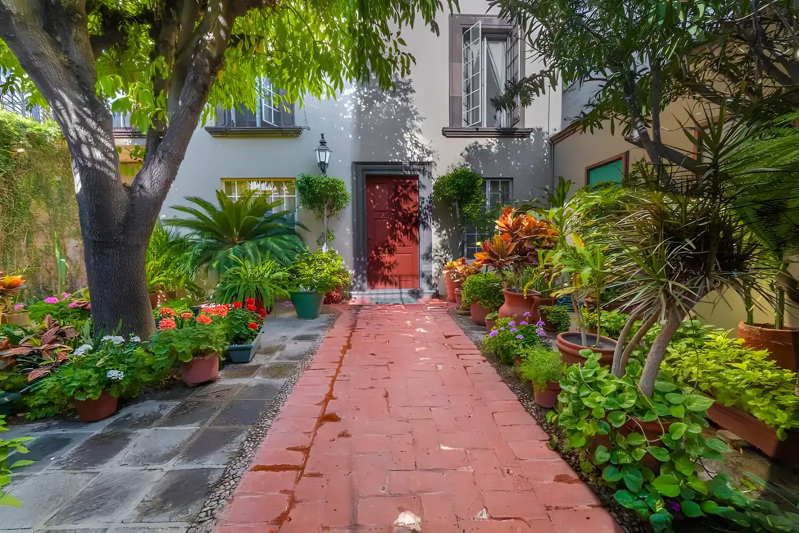 Casa de la Gracia, brick path through a flower garden to a red front door under a shade tree, San Miguel de Allende