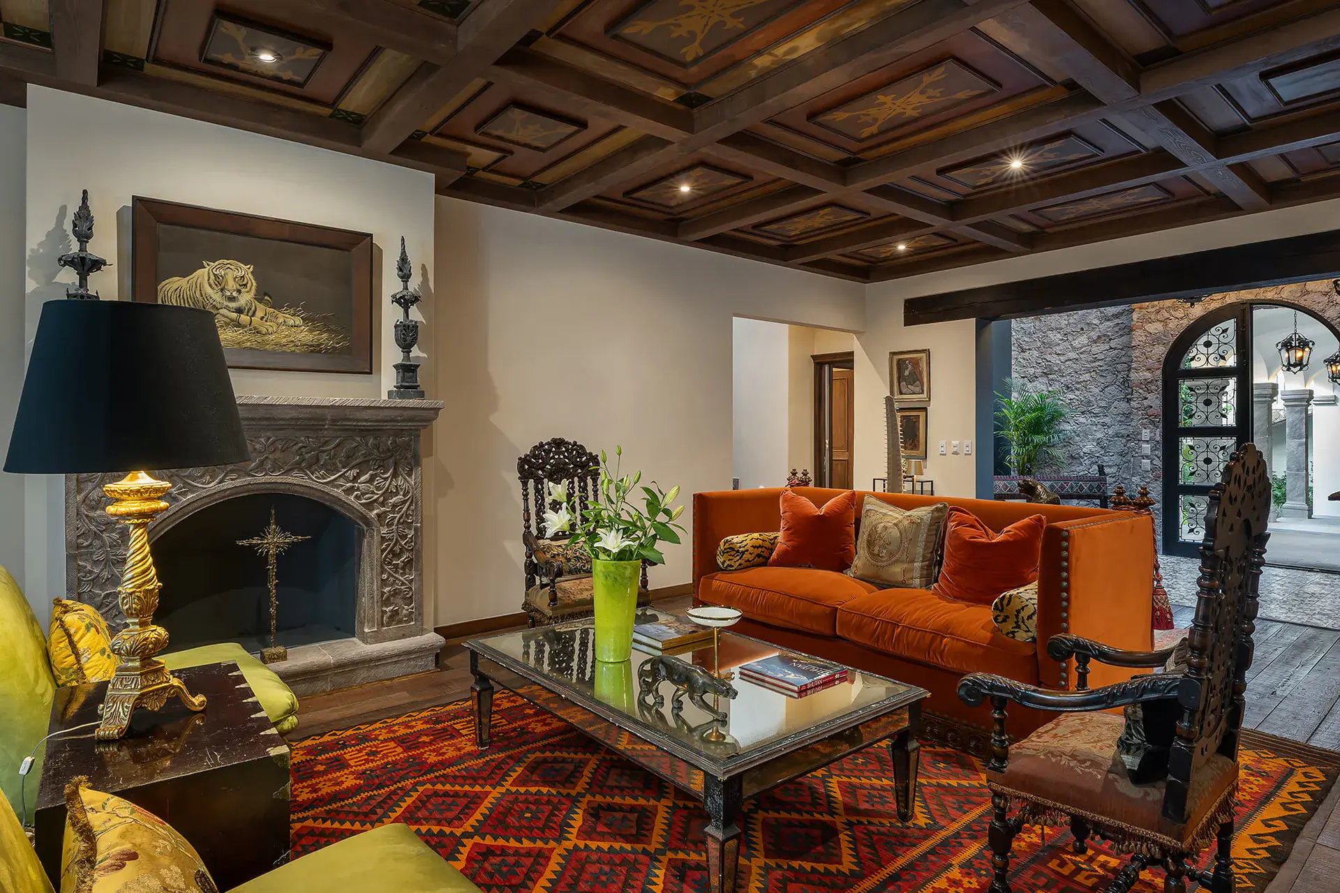 Casa de la Leona, living room with a stone fireplace, orange sofa and a coffered wood ceiling, San Miguel de Allende