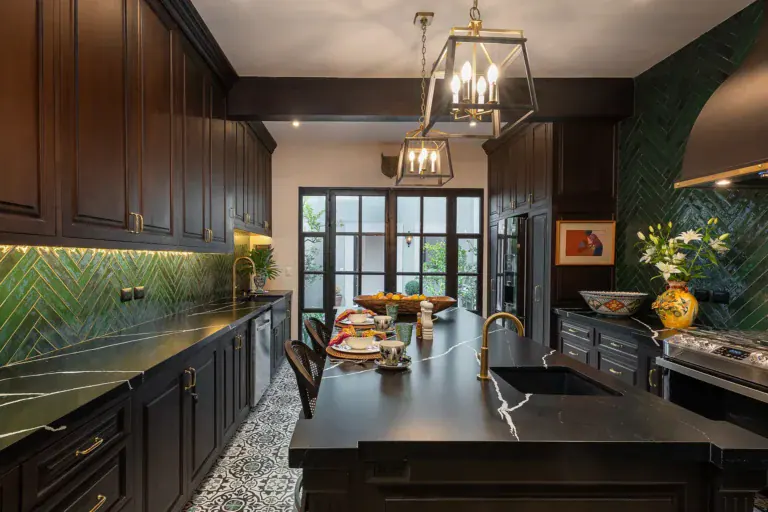Casa de la Leona, kitchen with dark cabinets, a black marble island and green herringbone tile, San Miguel de Allende