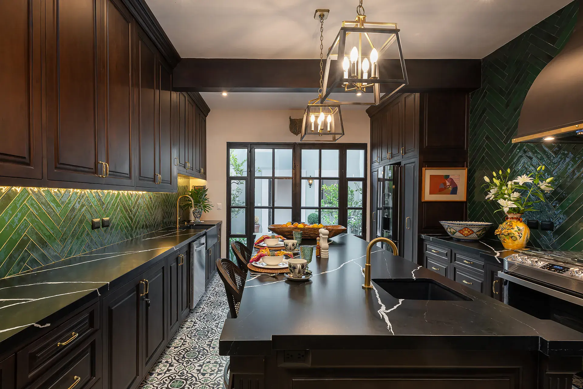 Casa de la Leona, kitchen with dark cabinets, a black marble island and green herringbone tile, San Miguel de Allende