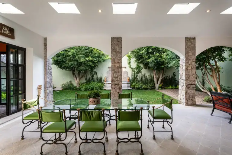 Casa de la Leona, covered garden dining area with a glass table and green chairs, San Miguel de Allende