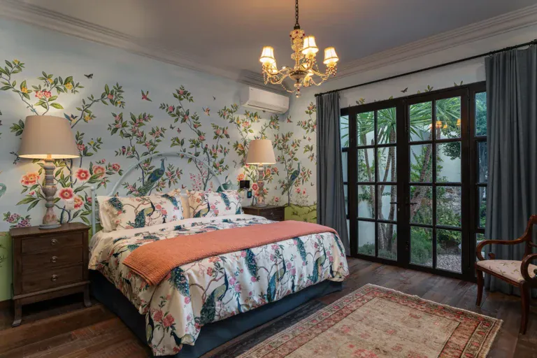 Casa de la Leona, bedroom with floral wallpaper, a chandelier and doors to the garden, San Miguel de Allende