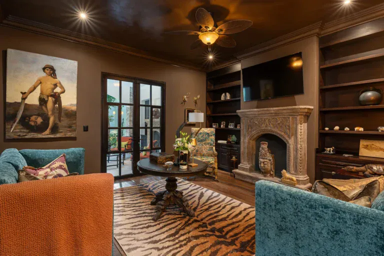 Casa de la Leona, den with a stone fireplace, built-in shelves and teal sofas, San Miguel de Allende