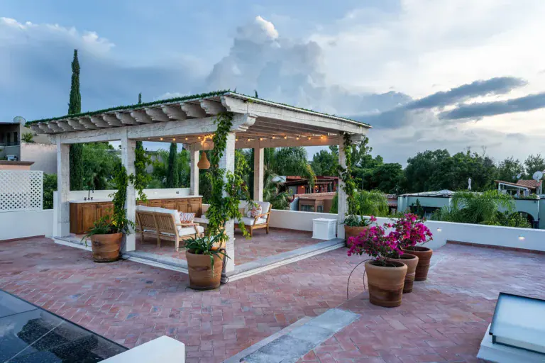 Casa de la Leona, rooftop terrace with a white pergola and potted plants at dusk, San Miguel de Allende