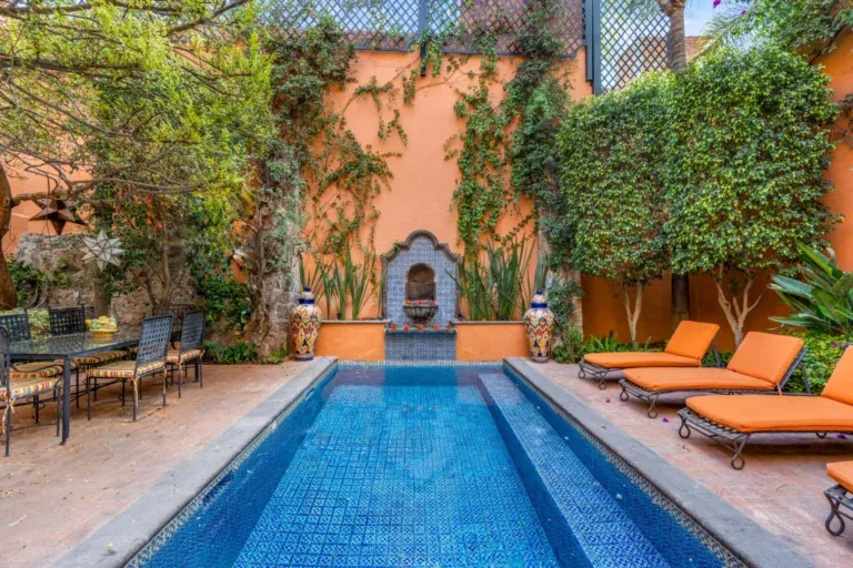 Casa de la Suerte, courtyard lap pool with orange loungers and a stone wall fountain, San Miguel de Allende