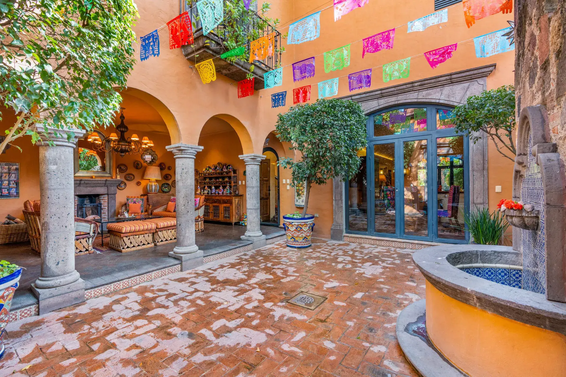 Casa de la Suerte, arcaded courtyard with a fountain, papel picado banners and a stone fireplace, San Miguel de Allende