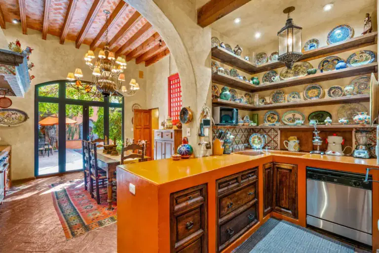 Casa de la Suerte, kitchen with an orange counter and open shelves of painted plates, San Miguel de Allende