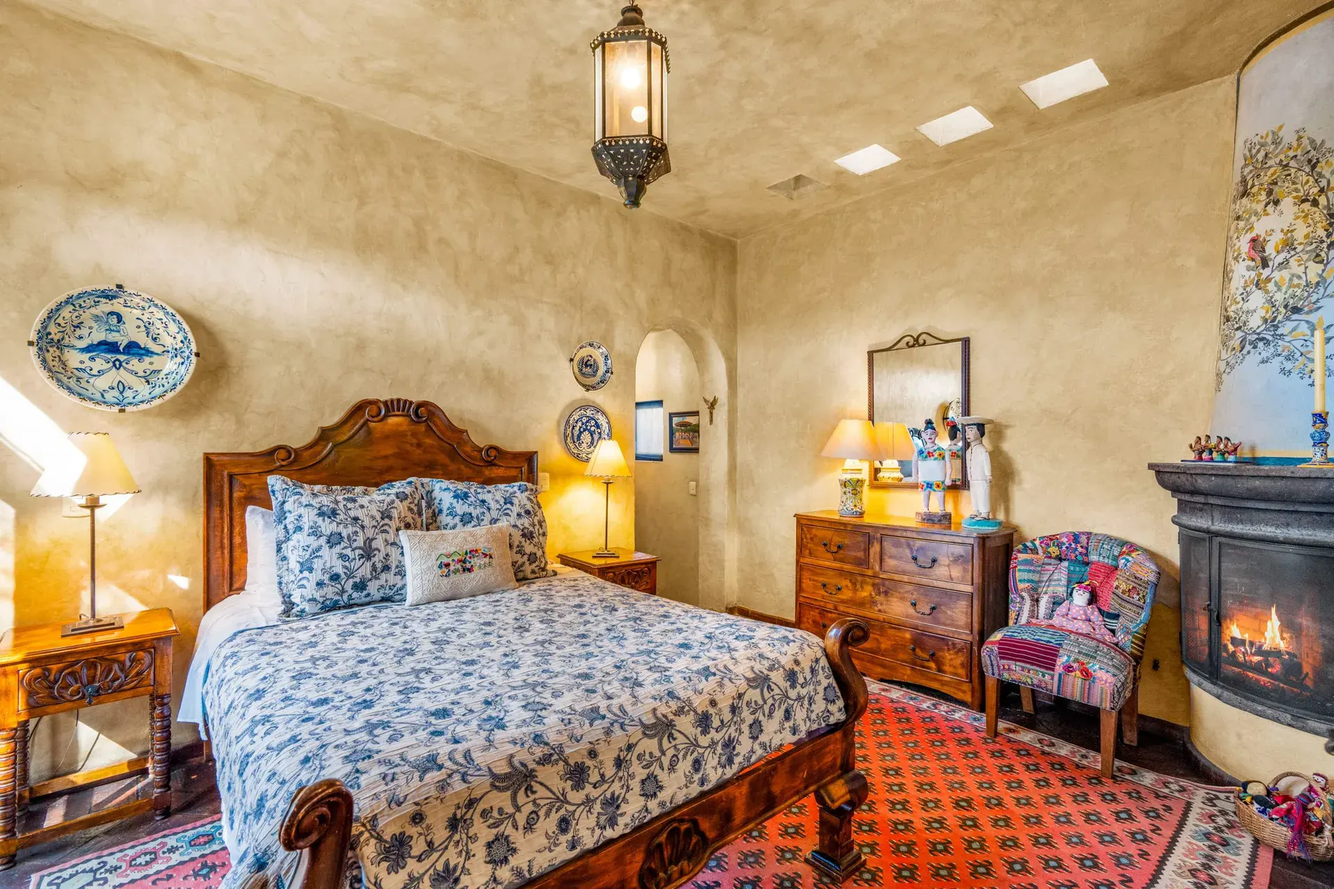 Casa de la Suerte, bedroom with a carved wood bed and a blue floral bedspread, San Miguel de Allende