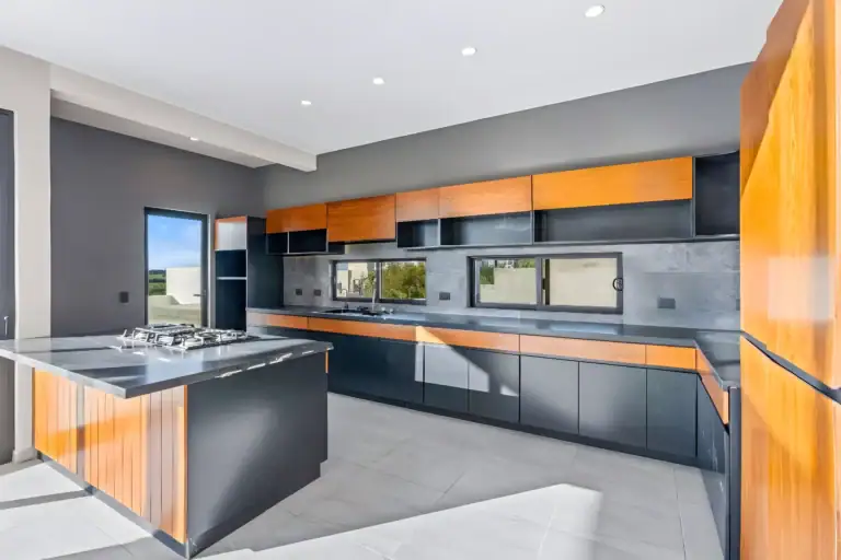 Casa de la Vista, kitchen with black and wood cabinets, a gray stone backsplash, a black granite counter and an island with a gas cooktop, San Miguel de Allende