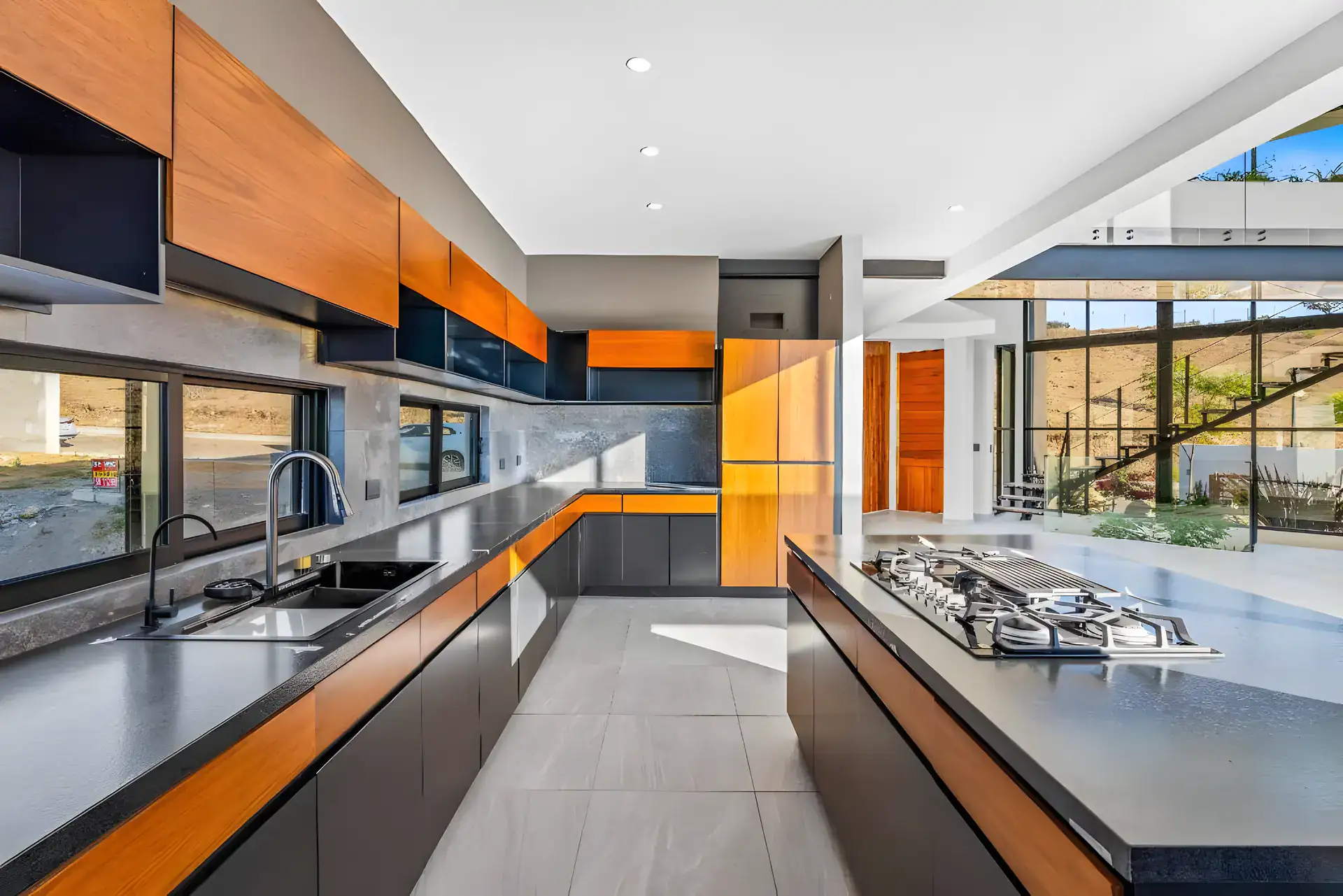 Casa de la Vista, kitchen with a long black counter, wood-trimmed cabinets, a double sink, an island and views to the hills, San Miguel de Allende